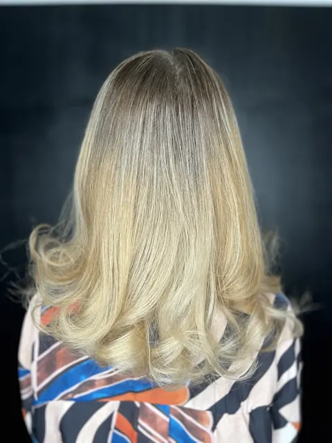 Păr blond cald, coafat cu bucle mari, fotografiat din spate pe fundal negru