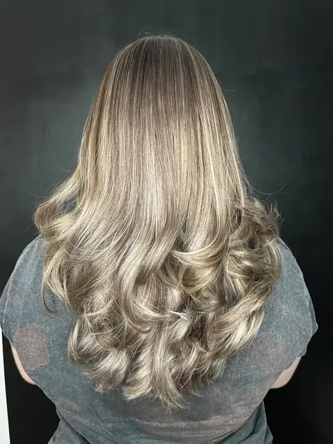 Păr lung cu șuvițe blond cenușiu și bucle la vârfuri, din spate, pe fundal negru
