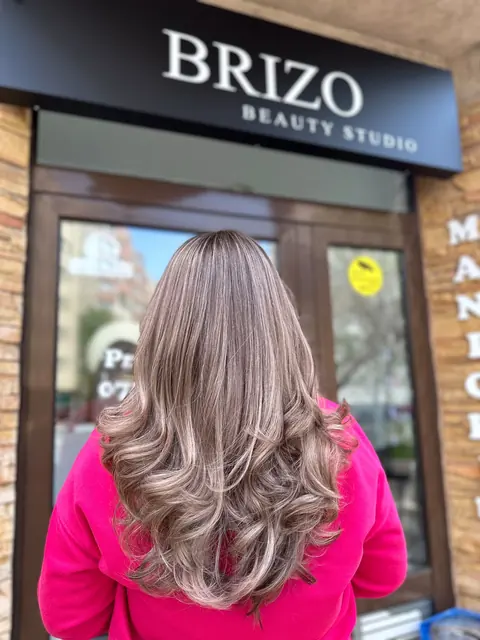 Păr lung, blond cu reflexe rosé, coafat cu bucle, în fața salonului Brizo Beauty Studio