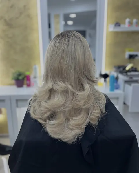 Păr blond cenușiu, coafat în valuri de la umeri în jos, din spate
